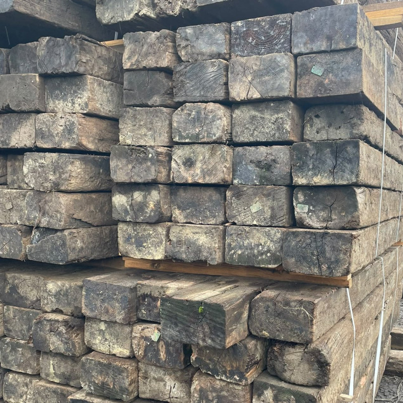 End grain of stacked reclaimed softwood railway sleepers showing growth rings and checks